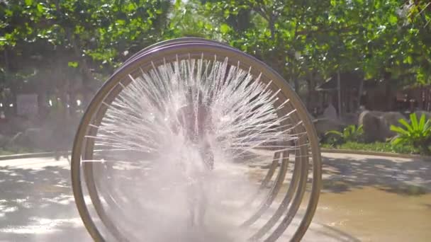 Une jeune femme court à travers une douche de massage circulaire dans un parc aquatique — Video