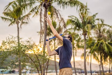 Tıbbi maske takan ve tenis oynayan bir adam. Coronavirus salgını Covid-19. Spor, karantinada aktif yaşam yüz maskesi korumalı cerrahi sterilizasyon. Corona Salgınında açık hava sporu
