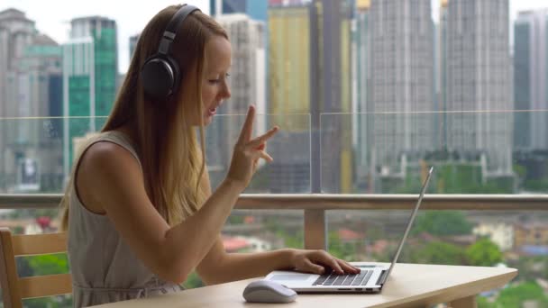 Remote techer har ett samtal med en student via internet på en balkong med en bakgrund av en stadskärna full av skyskrapor. Student väljer program för e-lärande, enkelt och effektivt — Stockvideo