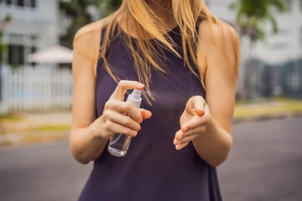 La donna in una piccola città con una maschera medica usa un disinfettante a causa di un'epidemia di coronovirus. — Foto Stock