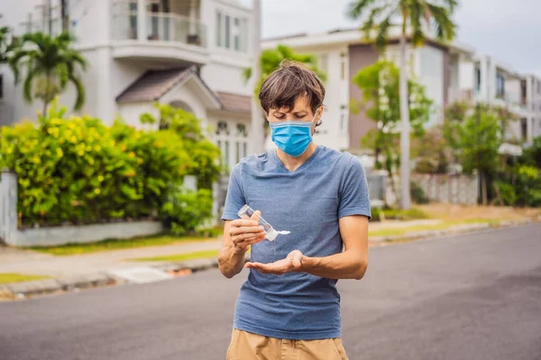 Egy férfi egy kisvárosban orvosi maszkban fertőtlenítőt használ a koszorúér járvány miatt. — Stock Fotó