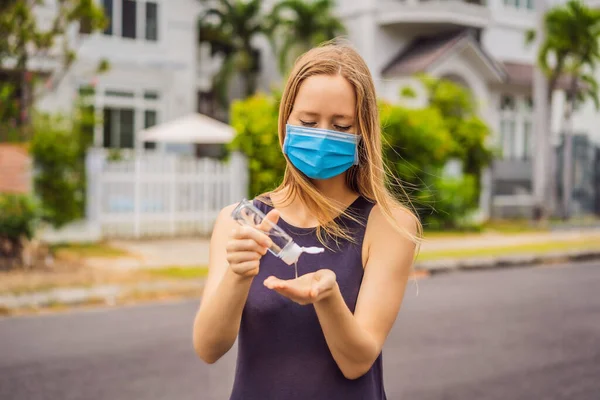 Женщина в маленьком городке в медицинской маске пользуется дезинфицирующим средством из-за эпидемии короновируса — стоковое фото
