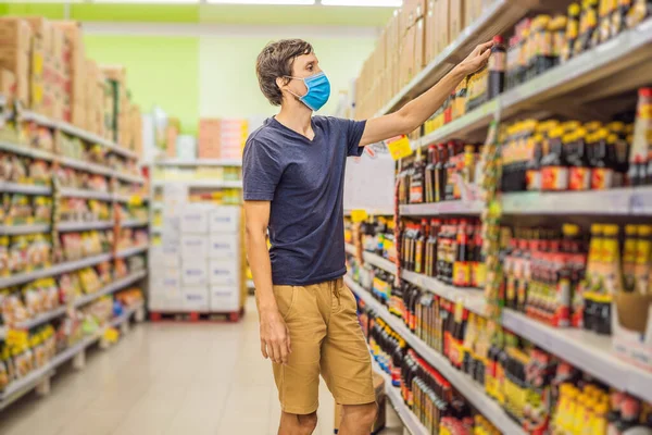 Тревожный мужчина носит медицинскую маску против коронавируса во время покупок в супермаркете или магазине - здоровье, безопасность и пандемия - молодая женщина в защитной маске и запасах продовольствия — стоковое фото