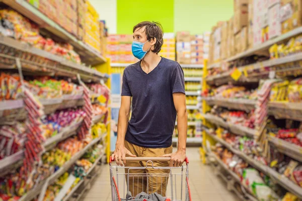 Alarmed man wears medical mask against coronavirus while grocery shopping in supermarket or store- health, safety and pandemic concept - young woman wearing protective mask and stockpiling food