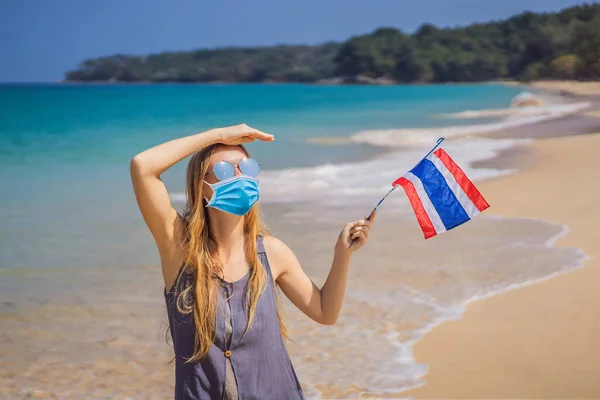 Mulher feliz em máscara médica se divertindo na praia com bandeira da Tailândia. Menina bonita que gosta de viajar para a Ásia Turistas temem o vírus 2019-ncov. turistas mascarados médicos — Fotografia de Stock