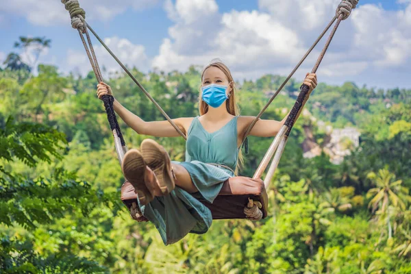 Junge Frau in medizinischer Maske schwingt im Dschungel-Regenwald der indonesischen Insel Bali. Schaukeln in den Tropen. Schaukeln - Trend Bali-Touristen fürchten das Virus 2019-ncov. Maskierte Touristen — Stockfoto