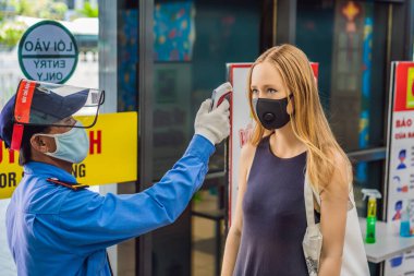 Vietnam, Nha Trang, 15.04.2020: Sağlık personeli kadın sıcaklığını kontrol ediyor. Bölgeye salgın Covid-19 ile girmeden önce