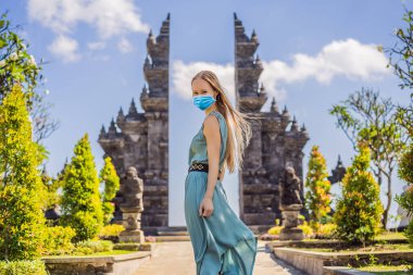 Young woman tourist in medical mask in budhist temple Brahma Vihara Arama Banjar Bali, Indonesia Tourists fear the 2019-ncov virus. Medical masked tourists clipart