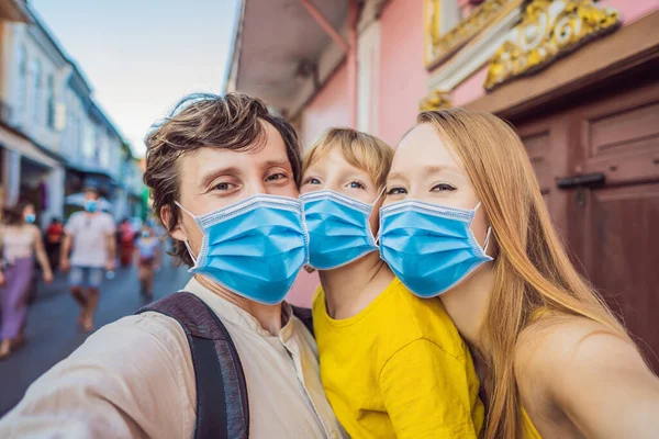 Mom, Dad and Son tourists in medical mask on the Street in the Portugese style Romani in Phuket Town. Also called Chinatown or the old town. Traveling with kids concept Tourists fear the 2019-ncov