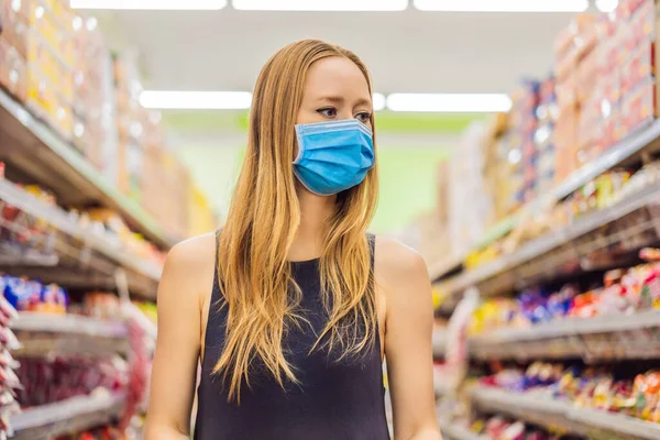 경계하고 있는 여성은 코로나 바이러스에 대항하여 의료용 마스크를 쓰고 슈퍼마켓이나 상점에서 식품을 사는 동안 건강, 안전, 유행병처럼 번지는 개념 - 보호용 마스크를 쓰고 식품을 비축하는 젊은 여성 — 스톡 사진