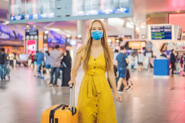 Beginn ihrer Reise. Schöne junge Frau mit medizinischer Maske in gelbem Kleid und gelbem Koffer wartet auf ihren Flug Touristen fürchten das Virus 2019-ncov. Maskierte Touristen — Stockfoto