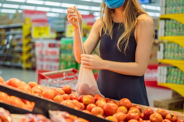 Een vrouw kiest tomaten in een supermarkt zonder een plastic zak te gebruiken. Herbruikbare tas voor het kopen van groenten. Nul afvalconcept — Stockfoto