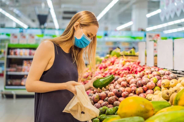 Vrouw kiest avocado in een supermarkt zonder gebruik te maken van een plastic zak. Herbruikbare tas voor het kopen van groenten. Nul afvalconcept — Stockfoto