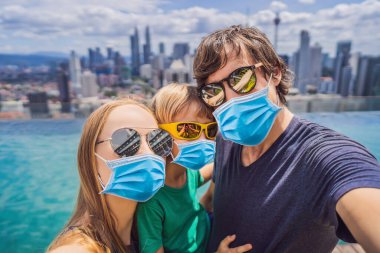 Tatil ve teknoloji. Mutlu aile sağlık maskesi, 2019-Ncov virüsünden korkan ve şehrin panoramik manzaralı havuz kenarında selfie çeken bir çocuk. Tıbbi maskeli turistler