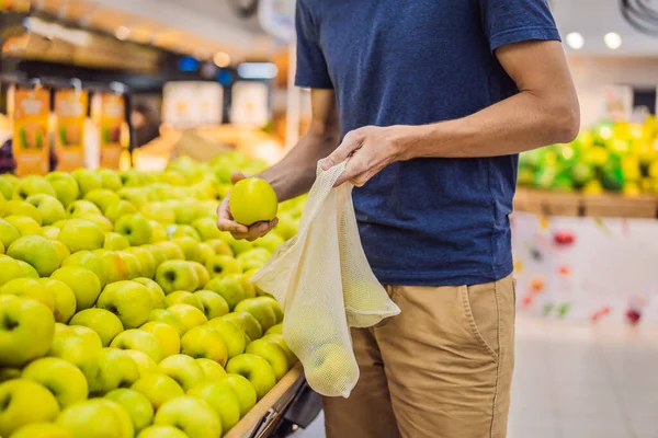 De mens kiest appels in een supermarkt zonder gebruik te maken van een plastic zak. Herbruikbare tas voor het kopen van groenten. Nul afvalconcept — Stockfoto