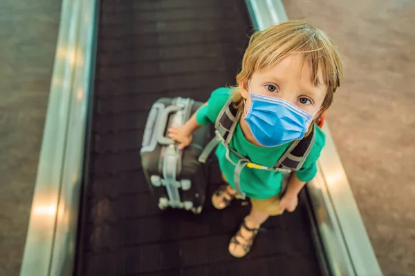 의료용 마스크를 쓰고 공항으로 휴가 여행을 가는 웃긴 소년, 실내 관광객들은 2019-ncov 바이러스를 두려워 한다. 의료용 마스크를 쓴 관광객 — 스톡 사진