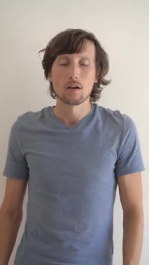 Dikey video. Genç bir adam doğru düzgün hapşırır. Dirseğine hapşırdı.