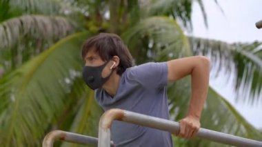 Genç bir adam yüksek parallettes dezenfekte ya da bir sokakta şınav çekiyor. Sonra egzersiz yapmaya başIıyor. Karantina sırasındaki fiziksel egzersizler.