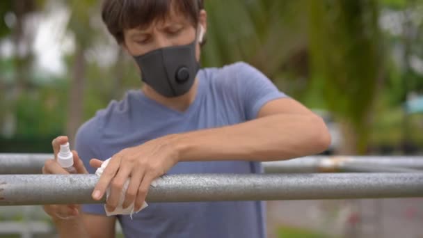 Ein junger Mann desinfiziert Hochparallelen oder Liegestühle auf einer Straße. Dann beginnt er mit Übungen. Körperliche Übungen während der Quarantäne — Stockvideo