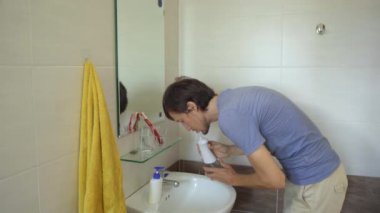 Genç bir adam dişlerini temizlemek için portatif bir diş ipi kullanıyor.