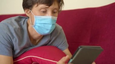E-kitap ve online eğitim. Bir adam karantina sırasında evde elektronik kitap okuyor. Tıbbi maskeli bir adam evde tek başına kaldı. Sonunda uykuya dalar..