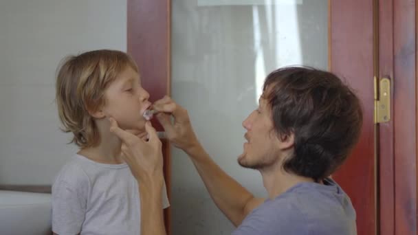 Um homem escova os dentes ao filho mais novo. Dentes conceito de cuidado — Vídeo de Stock