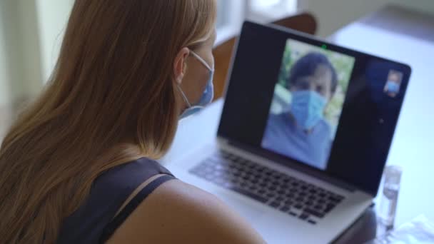 Genç bir kadın, Coronavirus 'un kendi kendini izole ettiği süre boyunca evinde otururken video konferans yoluyla konuşuyor. Sosyal uzaklık kavramı — Stok video