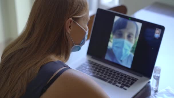 Een jonge vrouw praat via videoconferentie terwijl ze thuis zit tijdens de zelfisolatieperiode van het coronavirus. Sociaal afstandconcept — Stockvideo