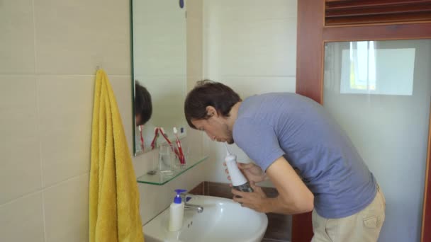 한 젊은 남자 가이를 닦기 위해 휴대 할 수있는 물대를 사용하는 구강 세척기 — 비디오