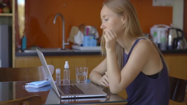 Een jonge vrouw praat via videoconferentie terwijl ze thuis zit tijdens de zelfisolatieperiode van het coronavirus. Sociaal afstandconcept — Stockvideo