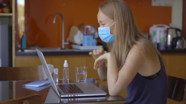 Une jeune femme parle par vidéoconférence alors qu'elle est assise à la maison pendant la période d'auto-isolement du coronavirus. Concept de distanciation sociale — Video