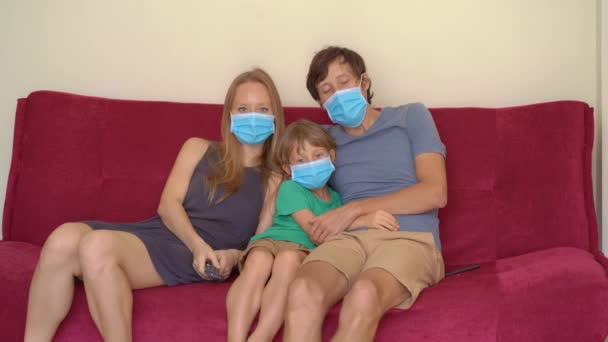Familie tijdens quarantaine tv kijken zittend op een bank. Zelfisolatieconcept — Stockvideo