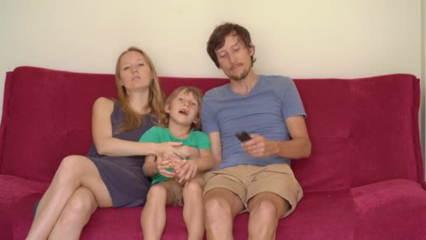 Семья во время карантина смотрит телевизор, сидя на диване. Концепция самоизоляции — стоковое видео