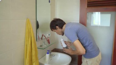 Genç bir adam dişlerini temizlemek için portatif bir diş ipi kullanıyor.