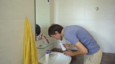 Genç bir adam dişlerini temizlemek için portatif bir diş ipi kullanıyor.