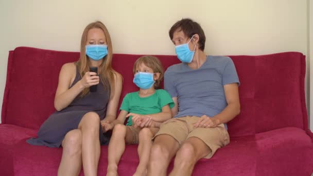 Famiglia durante la quarantena guardare la tv seduta su un divano. Concetto di autoisolamento — Video Stock