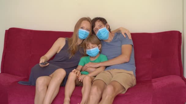 Family during quarantine watch tv sitting on a couch. Self-isolation concept — Stock Video