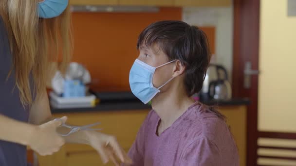 Una giovane donna fa tagli di capelli al suo fidanzato o marito a causa di isolamento. Sta cercando di seguire le istruzioni video. L'uomo ha paura che il suo taglio di capelli sarà terribile. Il concetto di isolamento sociale — Video Stock