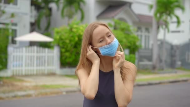 한 젊은 여성 이 의료용 마스크를 쓰고 있습니다. 그녀는 거리에 서 있습니다. 사회적 거리 개념. 감염 개념 — 비디오