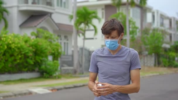 Uma jovem aplica um desinfetante em uma forma de gel em suas mãos em pé em uma rua. Conceito de distanciamento social. Conceito de desinfecção — Vídeo de Stock