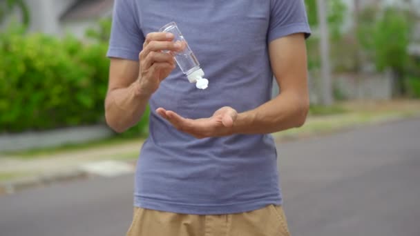 Mladá žena aplikuje dezinfekci v podobě gelu na jeho ruce stojící na ulici. Sociální distancování. Koncept dezinfekce — Stock video