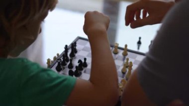 Genç adam ve oğlu karantina sırasında evde satranç oynuyorlar. Çocuklarla kendini soyutlama.
