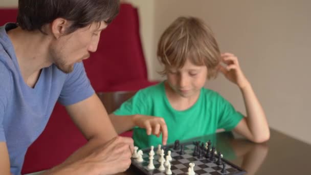 Während der Quarantäne spielen der junge Mann und sein Sohn zu Hause Schach. Selbstisolierung mit Kindern. — Stockvideo