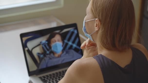 Een jonge vrouw praat via videoconferentie terwijl ze thuis zit tijdens de zelfisolatieperiode van het coronavirus. Sociaal afstandconcept — Stockvideo