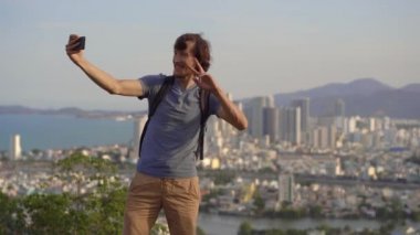Genç bir turist, Vietnam 'da ünlü bir turizm merkezi olan Nha Trang şehrine bakan dağda selfie çekiyor.