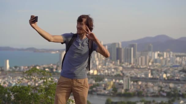 Un joven turista hace una selfie en la montaña con vistas a la ciudad de Nha Trang, un famoso destino turístico en Vietnam — Vídeos de Stock