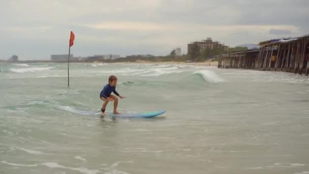 Инструктор по серфингу учит маленького мальчика серфингу — стоковое видео