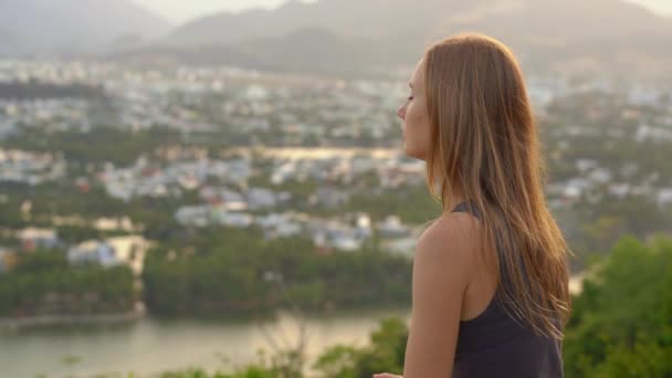 Una giovane donna medita su una montagna sopra una grande città. Concetto di pace interiore in una grande città — Video Stock