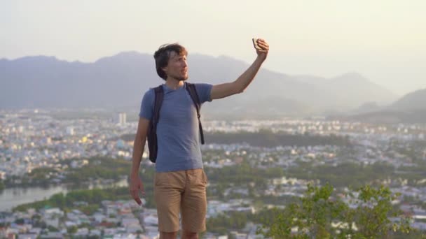 En ung man turist gör en selfie på miuntaing med utsikt över Nha Trang stad, en berömd turistmål i Vietnam — Stockvideo