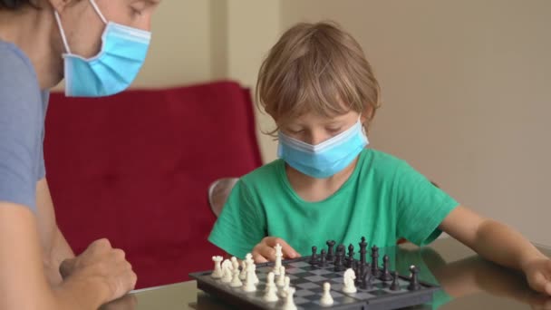 Während der Quarantäne spielen der junge Mann und sein Sohn zu Hause Schach. Selbstisolierung mit Kindern. — Stockvideo